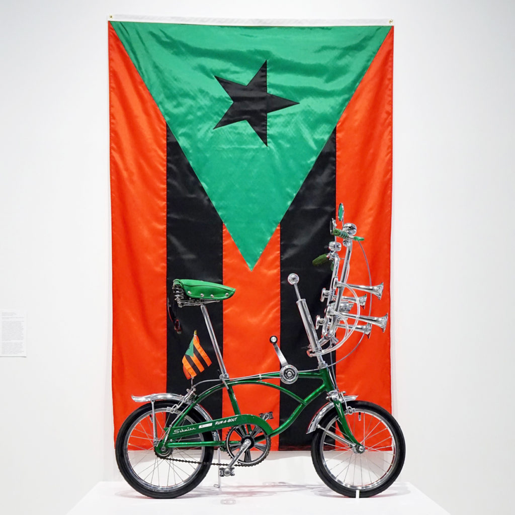 RUN-A-BOUT, 2017 1969 Schwinn Run-A-Bout, chrome machete, flags 48" x 60" x 26." Puerto Rican Flag in Red, Black and Green, 2017 96" x 60." Courtesy the artist. 