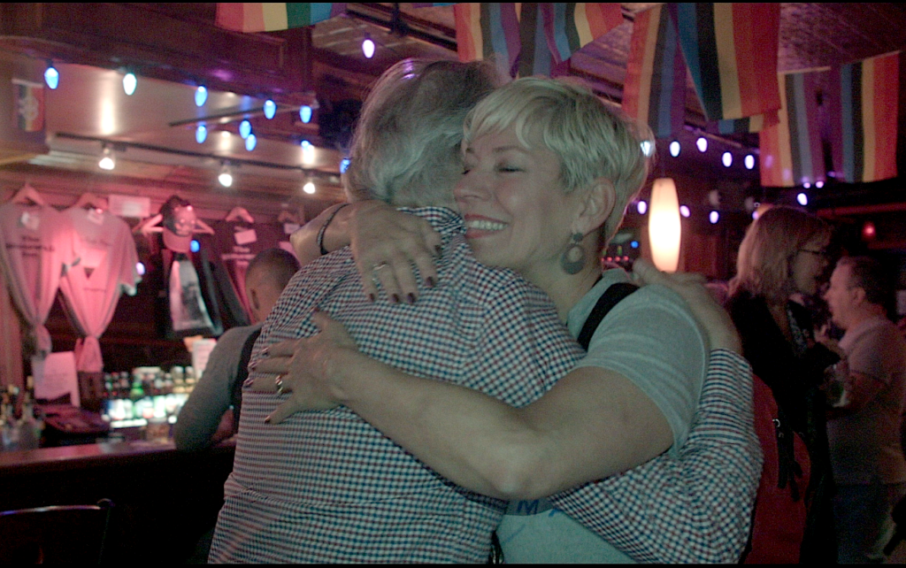 Sara gives out free hugs at Stonewall Inn at the end of the first Free Mom Hugs Tour, photo courtesy the artist.
