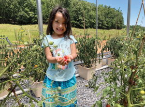 A Maskoke child holds tomatoes grown in the Ecovillage greenhouses. Residents grow vegetables based on the traditional diets of their ancestors.